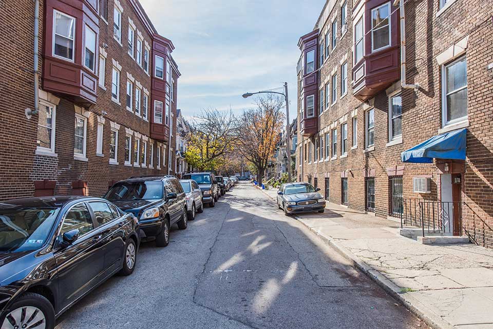 Street with cars and apartments in Spruce Hill, Philadelphia, PA